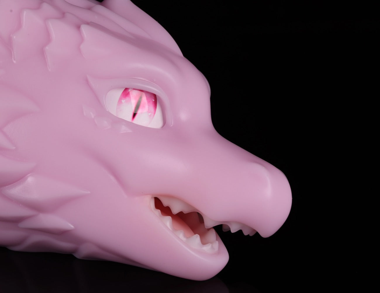 Close-up on the piercing red eye and smooth facial anatomy of dimvra-figurine pink dragon collectible.